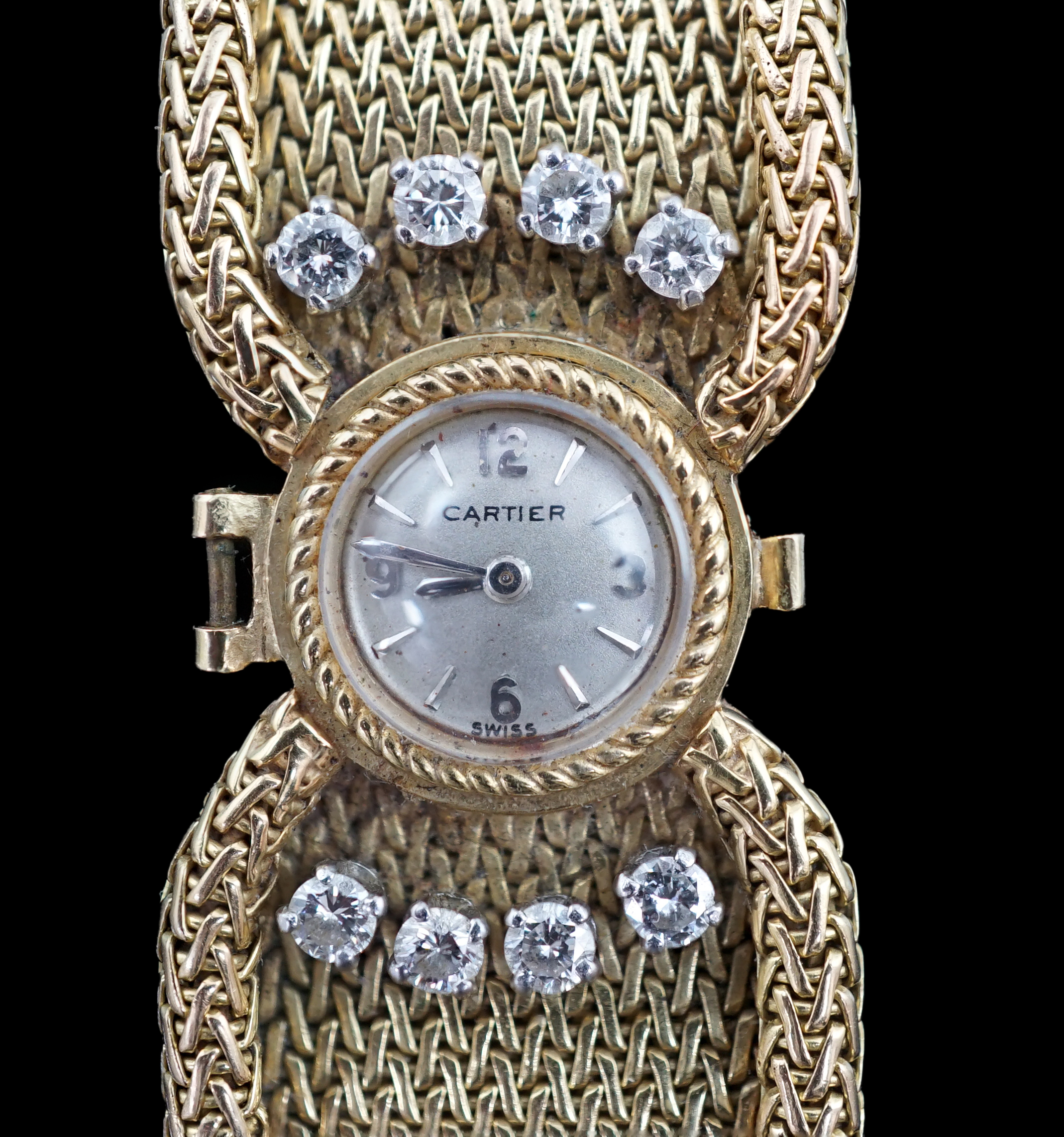 A lady's 18ct gold and eight stone diamond set manual wind cocktail, the dial inscribed Cartier, on integral tapered gold bracelet set with eight round cut stones